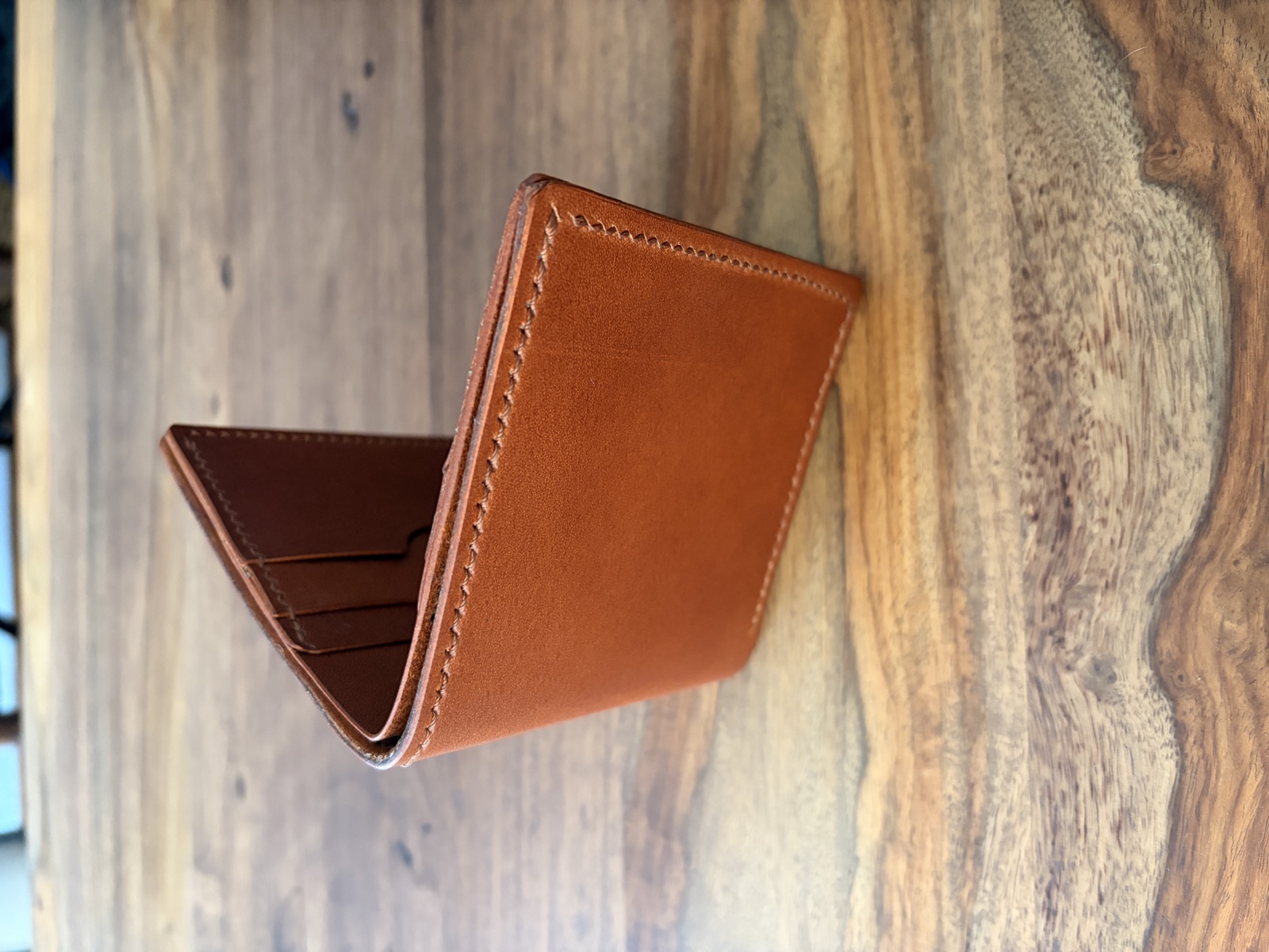 The Heritage bifold wallet standing open, showing hand-stitched edges